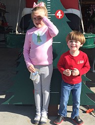 Children posing with the growing tree to mark another year of love and memories at the Kiser Christmas Tree Market