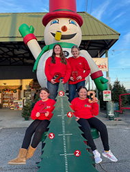 Children posing with the growing tree to mark another year of love and memories at the Kiser Christmas Tree Market
