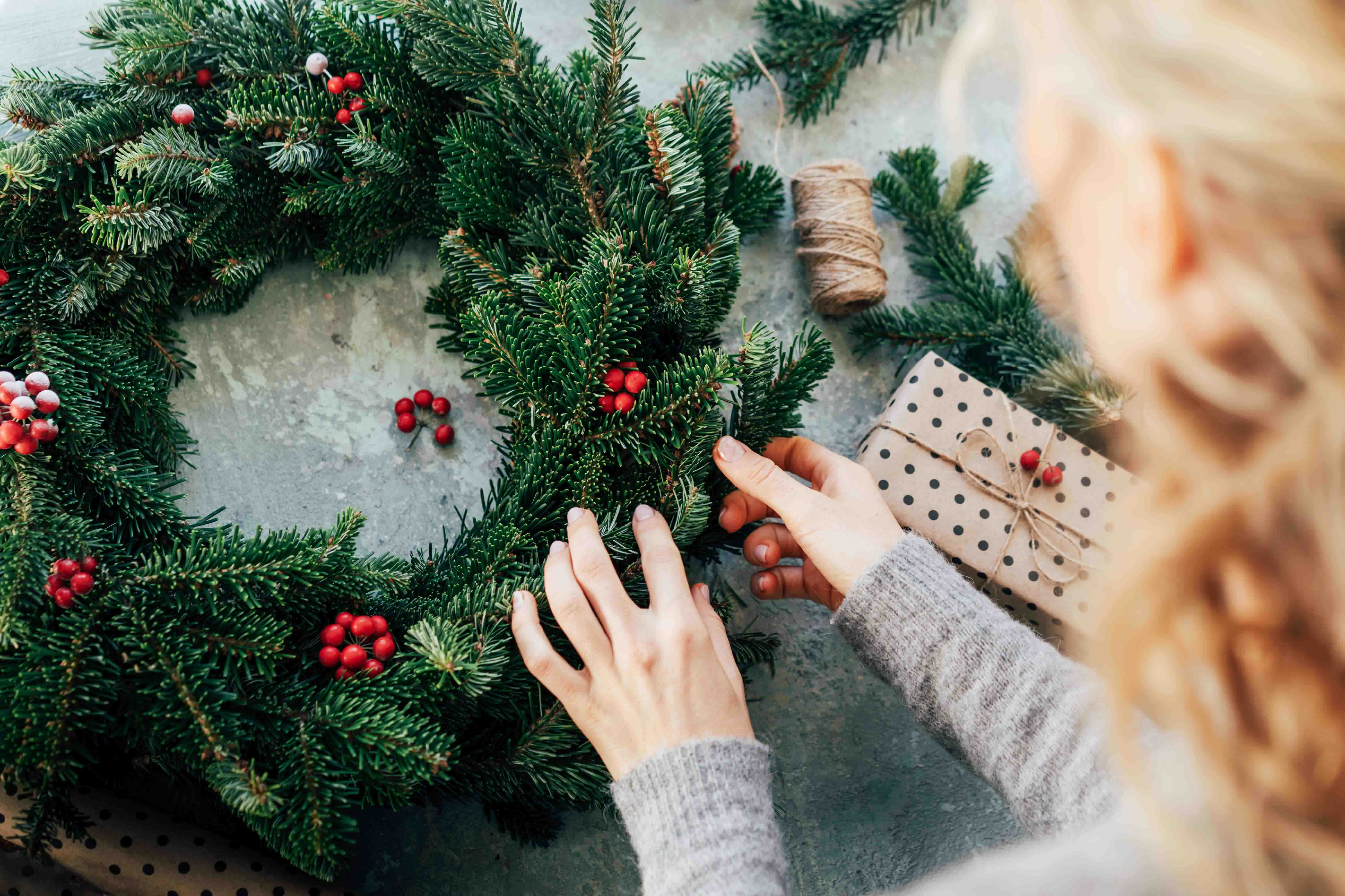 A hand making a fresh christmas wreath from pine branches.