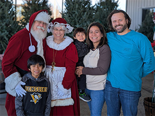 Children posing with the growing tree to mark another year of love and memories at the Kiser Christmas Tree Market